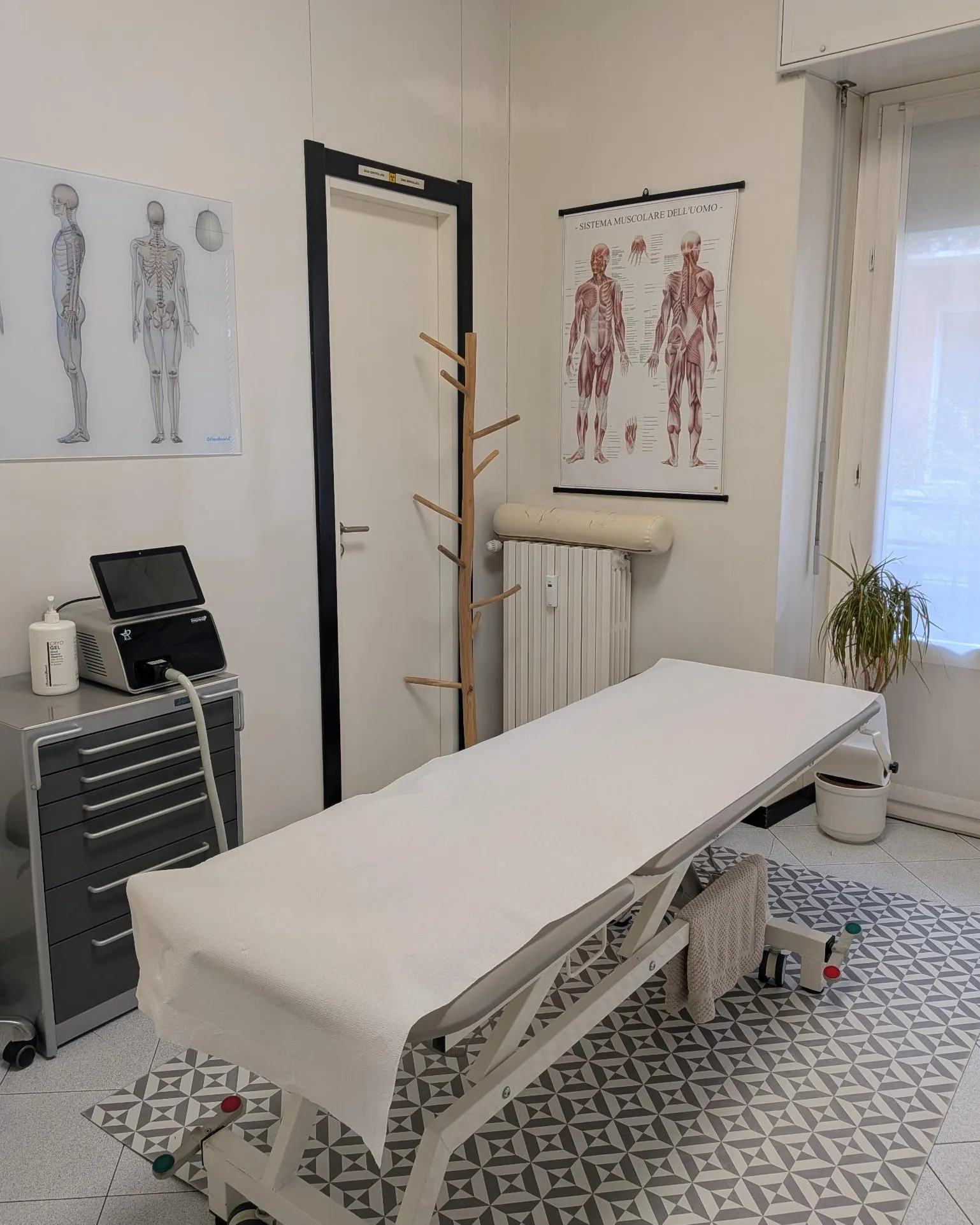 Sala trattamenti con lettino elettrico e tavole anatomiche