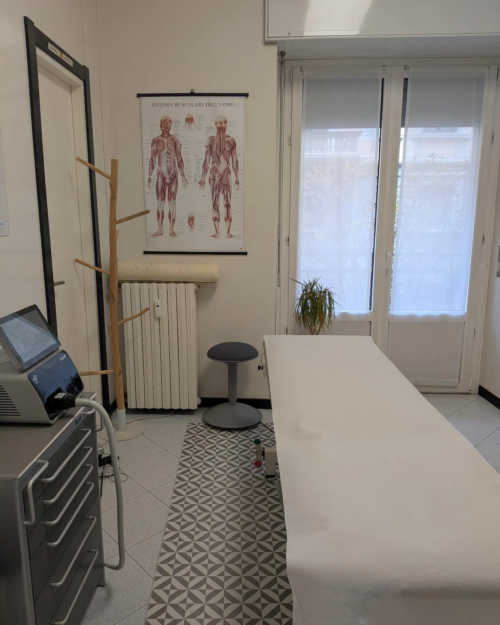 Sala trattamenti luminosa con lettino, tavola anatomica e apparecchio per terapia strumentale