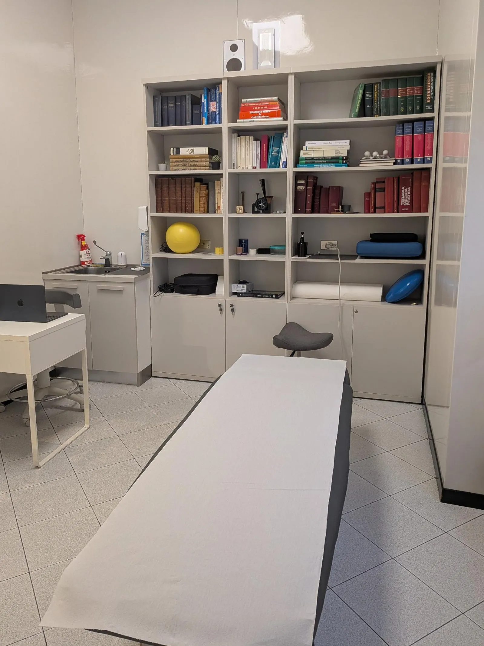 Sala trattamenti con lettino e libreria